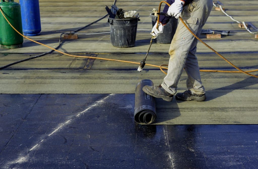 Worker preparing bitumen roofing felt roll